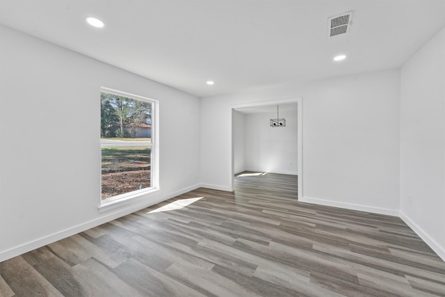 spare room with wood-type flooring and an inviting chandelier