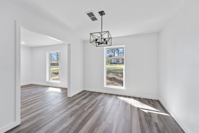 unfurnished dining area with hardwood / wood-style flooring and a notable chandelier