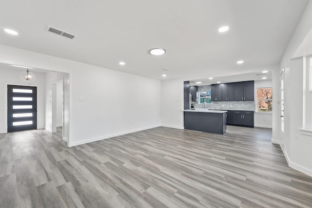 kitchen with light hardwood / wood-style flooring, a center island, and decorative backsplash