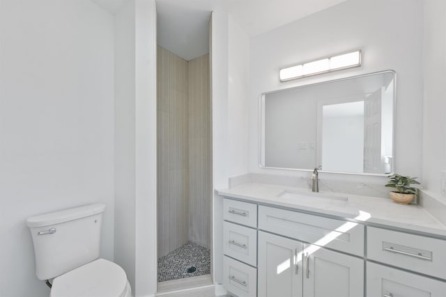 bathroom featuring toilet, tiled shower, and vanity