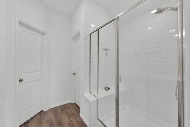 bathroom featuring a shower with shower door and hardwood / wood-style flooring