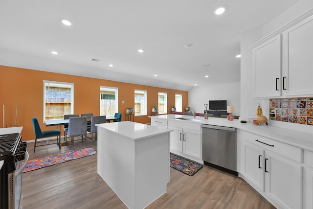 kitchen featuring stainless steel appliances, backsplash, kitchen peninsula, light hardwood / wood-style floors, and white cabinets