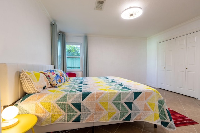 bedroom with tile patterned floors, ornamental molding, and a closet