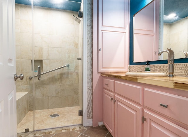 bathroom with tile patterned floors, vanity, an enclosed shower, and tasteful backsplash