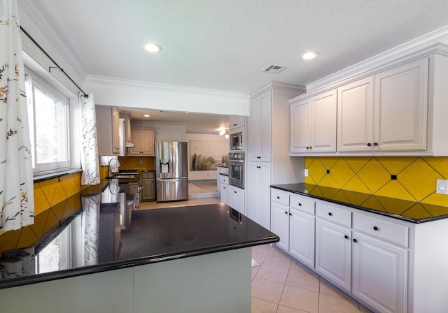 kitchen with light tile patterned flooring, white cabinets, ornamental molding, and appliances with stainless steel finishes