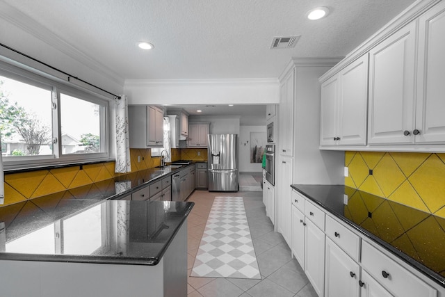 kitchen with ornamental molding, stainless steel appliances, sink, light tile patterned floors, and white cabinetry