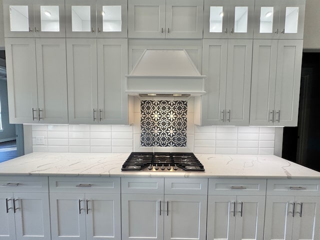 kitchen featuring stainless steel gas stovetop, white cabinetry, and premium range hood