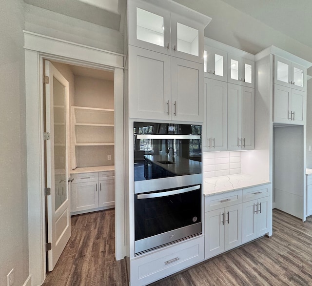 kitchen with white cabinets, dark hardwood / wood-style flooring, light stone countertops, and double wall oven