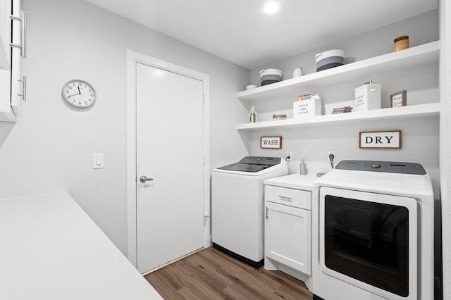 clothes washing area with washing machine and dryer, dark wood-type flooring, and cabinets