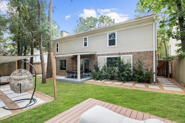 rear view of house with a wooden deck, a patio area, and a lawn