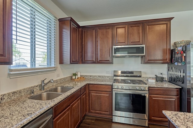 kitchen with light stone countertops, appliances with stainless steel finishes, dark hardwood / wood-style floors, and sink