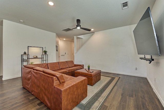 living room with ceiling fan, dark wood-type flooring, visible vents, and baseboards