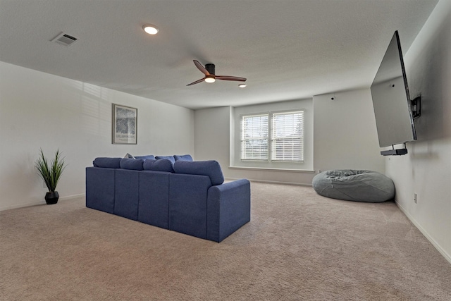 carpeted living room featuring ceiling fan and a textured ceiling