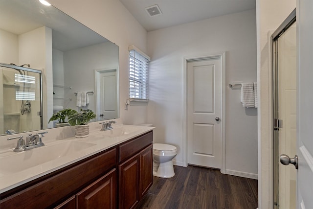 bathroom featuring wood-type flooring, vanity, toilet, and a shower with door