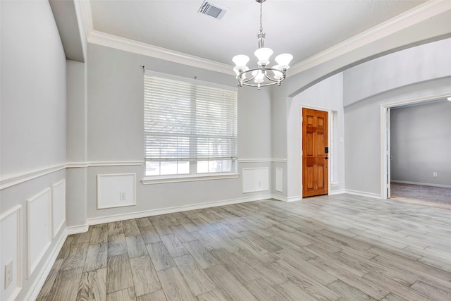 spare room with an inviting chandelier, ornamental molding, and light hardwood / wood-style flooring