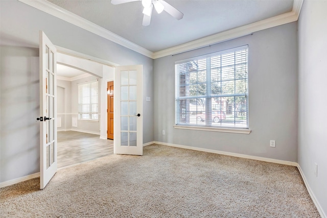 carpeted empty room featuring french doors, ceiling fan, a wealth of natural light, and ornamental molding