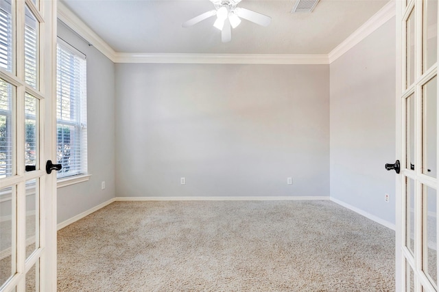 empty room with ornamental molding, ceiling fan, french doors, and carpet flooring