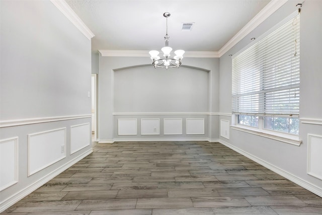 unfurnished dining area featuring dark hardwood / wood-style flooring, crown molding, and a notable chandelier