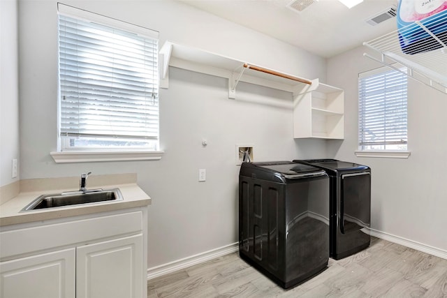 laundry area featuring sink, washing machine and dryer, and light wood-type flooring