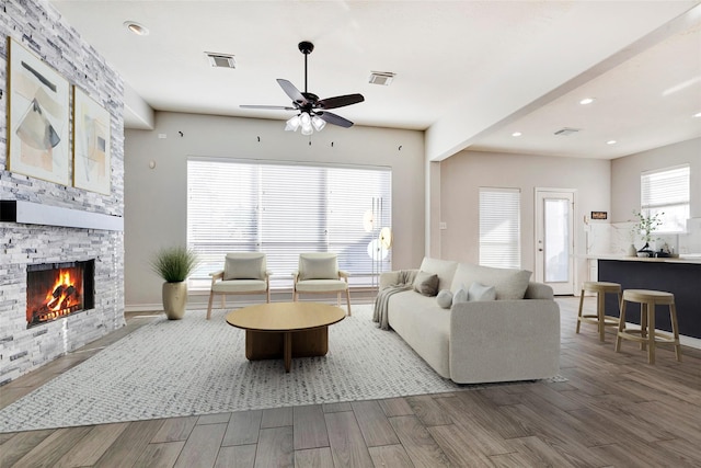 living room featuring ceiling fan, plenty of natural light, and a fireplace