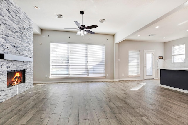 unfurnished living room featuring ceiling fan and a fireplace