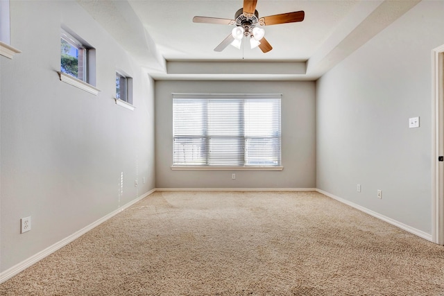 carpeted spare room featuring a raised ceiling and ceiling fan