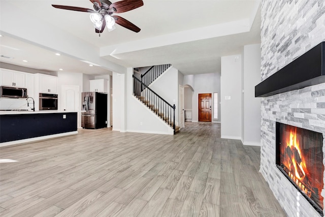 unfurnished living room with a fireplace, ceiling fan, and light hardwood / wood-style floors