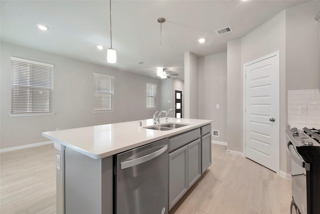 kitchen with appliances with stainless steel finishes, sink, gray cabinetry, hanging light fixtures, and a center island with sink