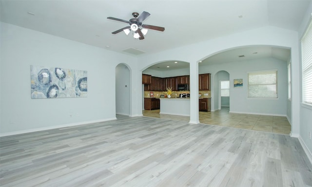 unfurnished living room with light hardwood / wood-style flooring, vaulted ceiling, and ceiling fan