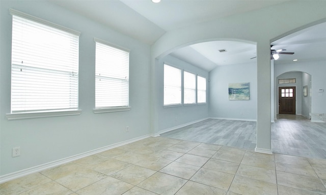 tiled empty room with ceiling fan and vaulted ceiling