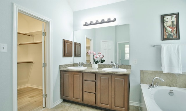 bathroom with a tub to relax in, tile patterned flooring, and vanity