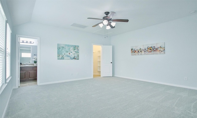 unfurnished bedroom featuring light carpet, ceiling fan, a spacious closet, connected bathroom, and lofted ceiling