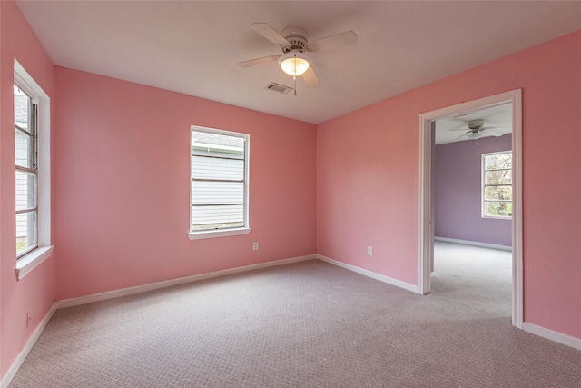 carpeted empty room featuring a wealth of natural light and ceiling fan