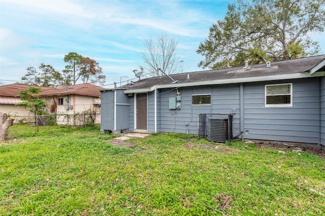 back of property featuring central air condition unit and a lawn