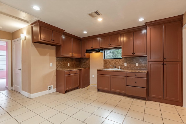 kitchen with backsplash, sink, light tile patterned flooring, and stone countertops