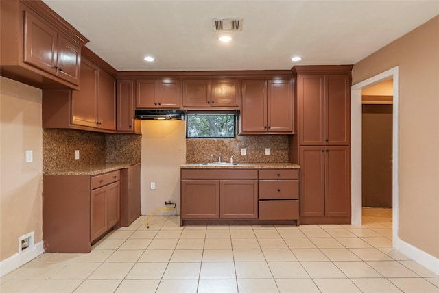 kitchen with tasteful backsplash, light stone countertops, sink, and light tile patterned flooring