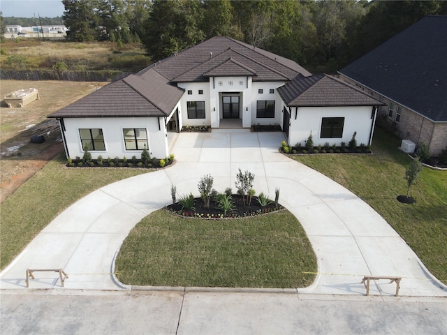 view of front facade featuring driveway, stucco siding, a tiled roof, and a front yard