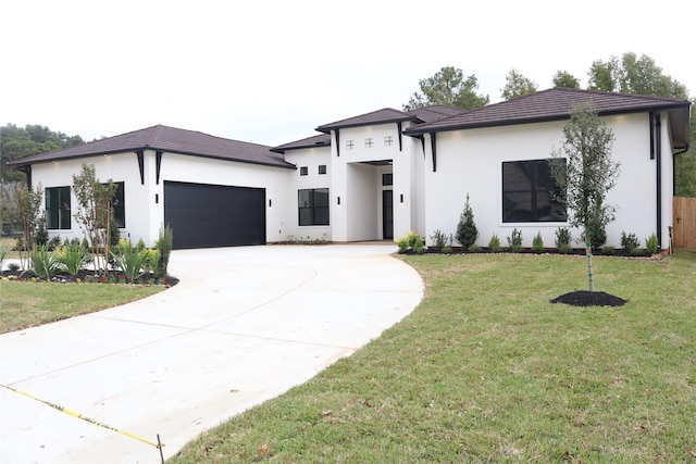 prairie-style house with driveway, stucco siding, an attached garage, and a front yard