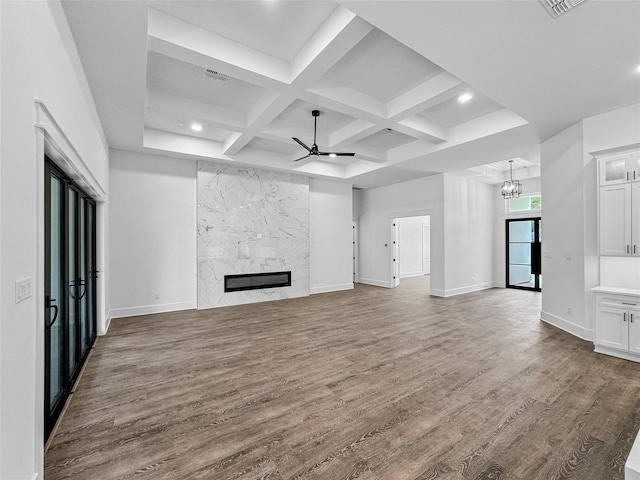 unfurnished living room featuring hardwood / wood-style floors, coffered ceiling, ceiling fan with notable chandelier, a fireplace, and beam ceiling