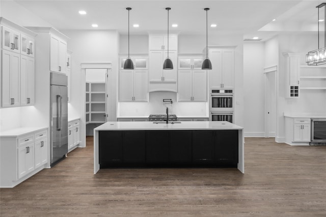 kitchen featuring white cabinets, an island with sink, and hanging light fixtures