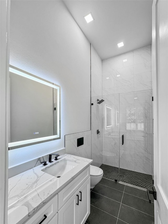 bathroom featuring tile patterned floors, vanity, toilet, and a shower with door