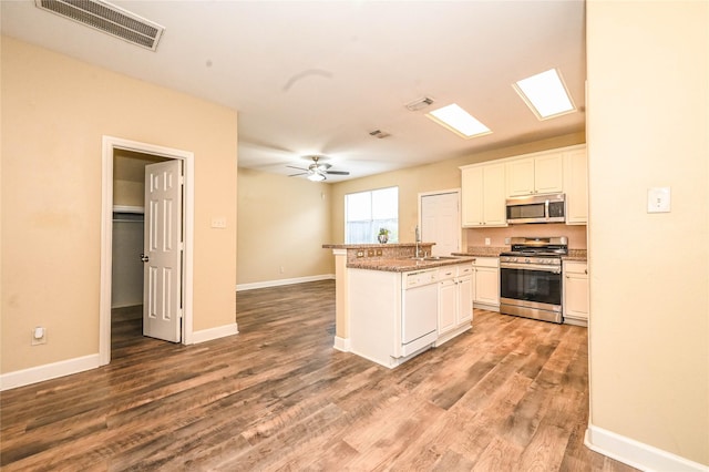 kitchen featuring sink, an island with sink, appliances with stainless steel finishes, white cabinetry, and wood-type flooring