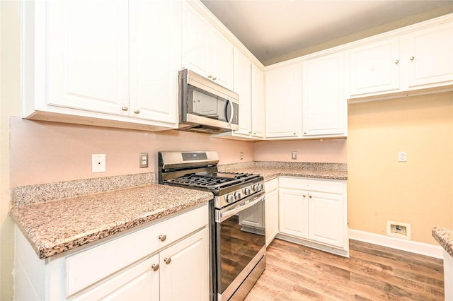 kitchen featuring light stone countertops, appliances with stainless steel finishes, light hardwood / wood-style floors, and white cabinetry