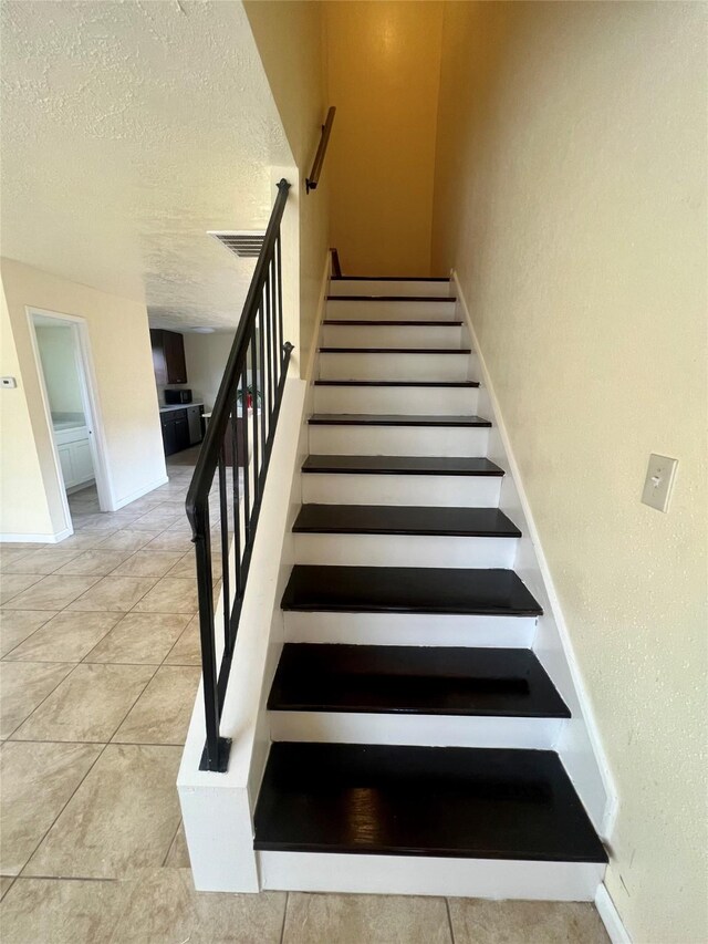 staircase with tile patterned flooring and a textured ceiling