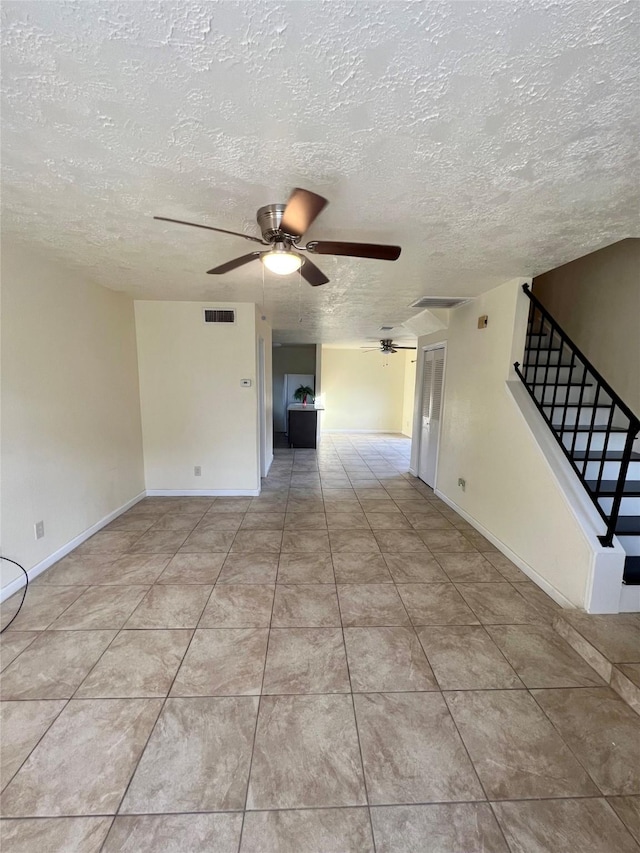 tiled empty room featuring ceiling fan and a textured ceiling