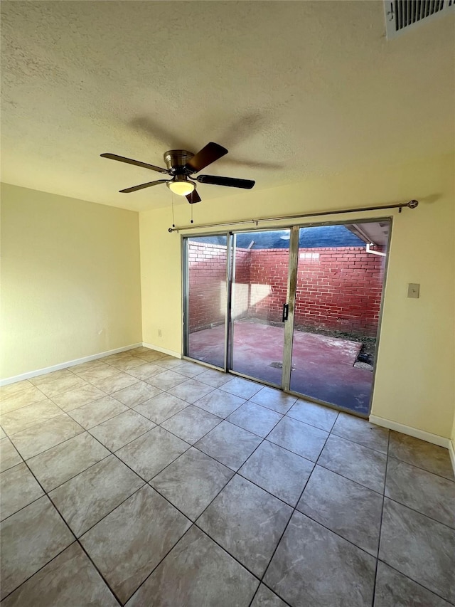 empty room featuring ceiling fan, light tile patterned flooring, and a textured ceiling