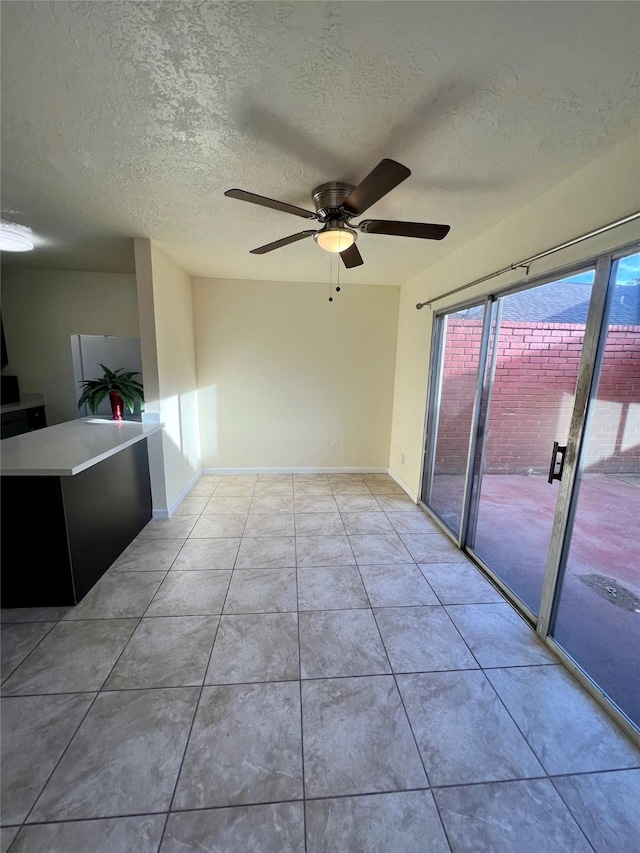 spare room with ceiling fan, light tile patterned floors, and a textured ceiling