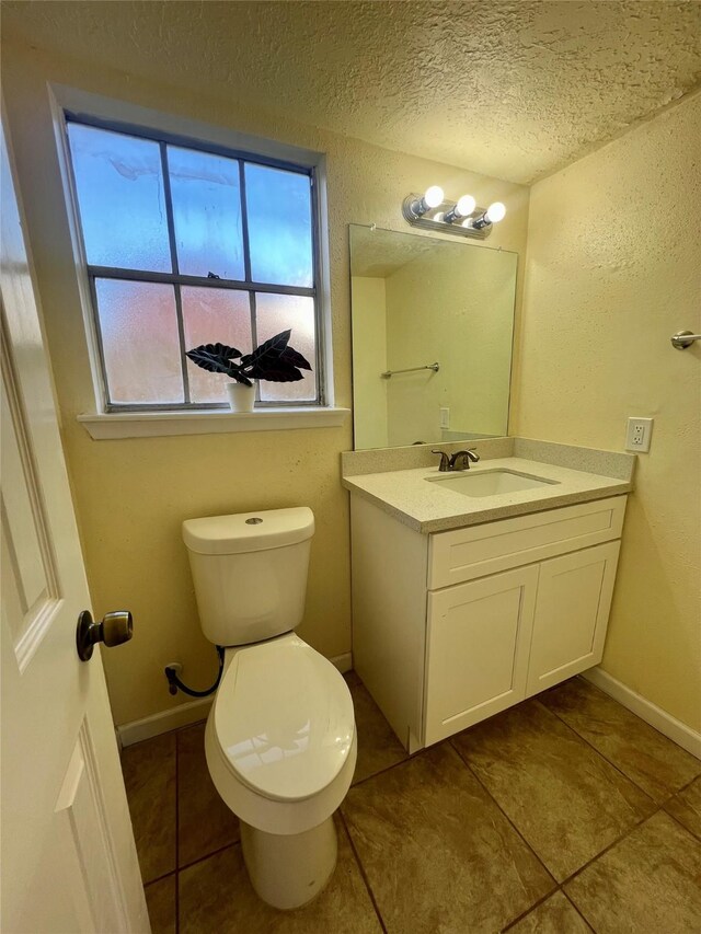 bathroom with tile patterned flooring, vanity, a textured ceiling, and toilet