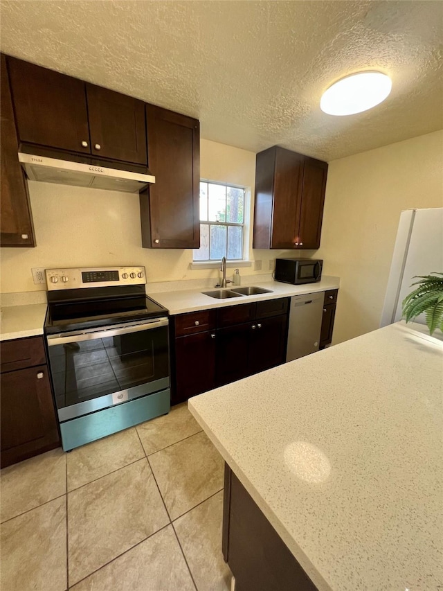 kitchen with dark brown cabinetry, sink, stainless steel appliances, and a textured ceiling