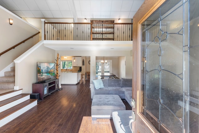 living room featuring dark hardwood / wood-style floors, a notable chandelier, and a towering ceiling